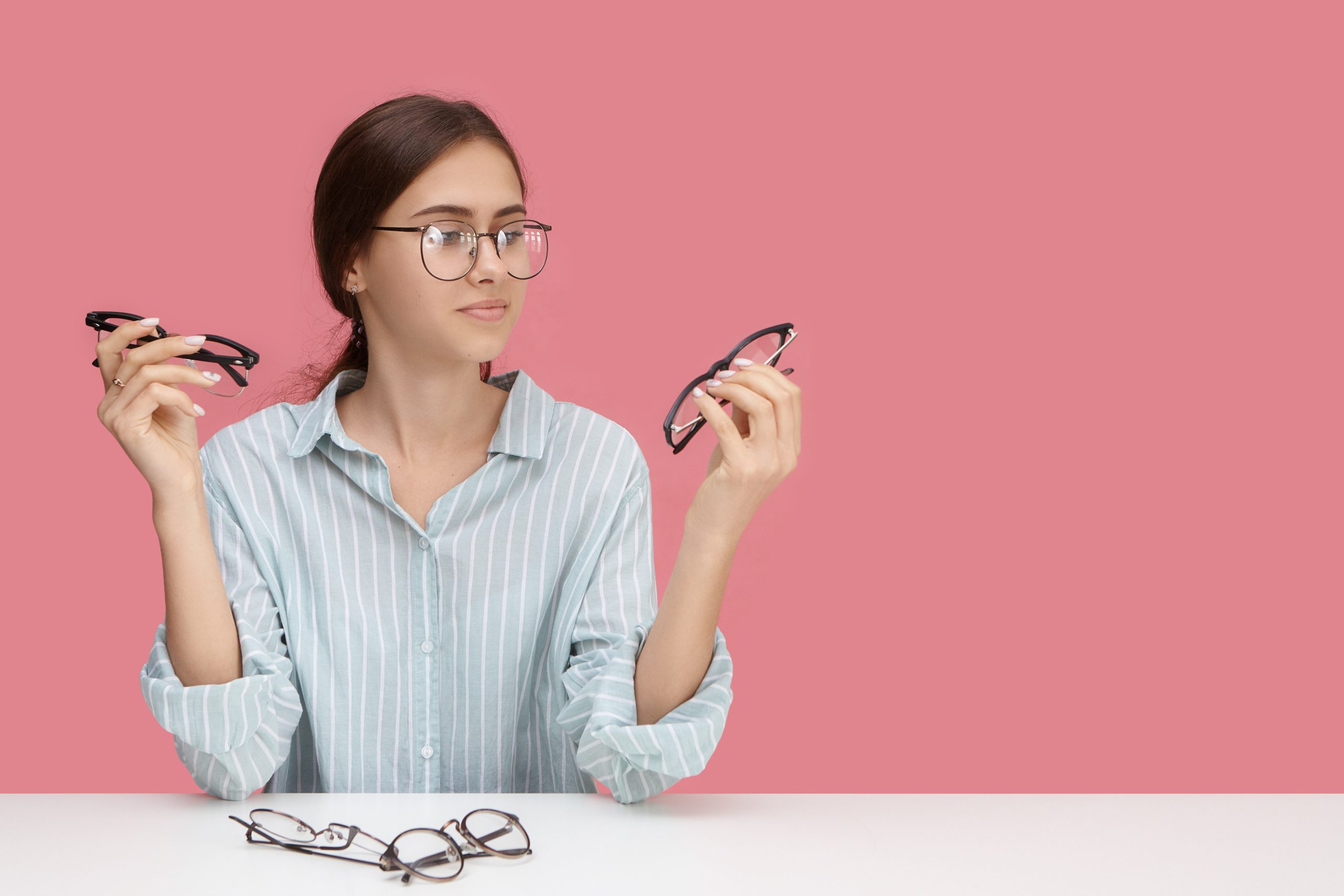 Woman choosing between multiple pairs of eyeglasses